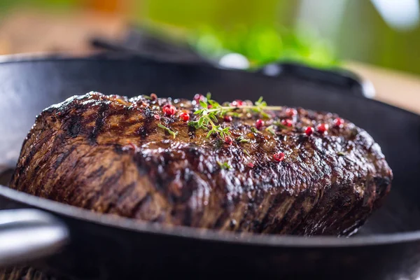 Nötstek. Saftig entrecôte stek i stekpanna på träskiva med ört och peppar — Stockfoto