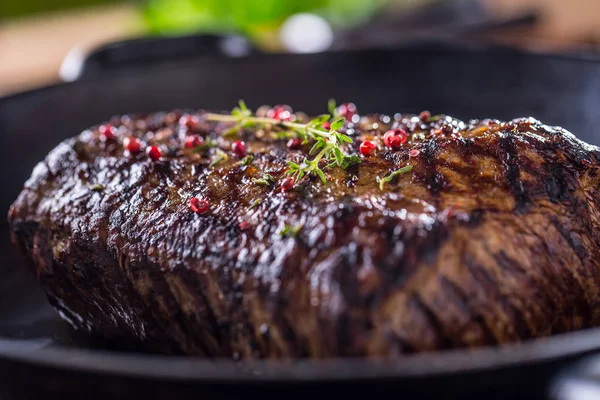 Sığır eti biftek. Ot ve biber ile ahşap tahta üzerinde tavada sulu kaburga eti