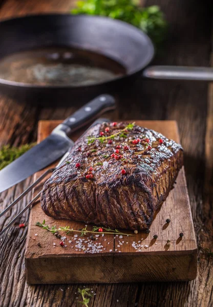 Carne de res. Juicy Rib Eye filete en sartén sobre tabla de madera con hierba y pimienta — Foto de Stock