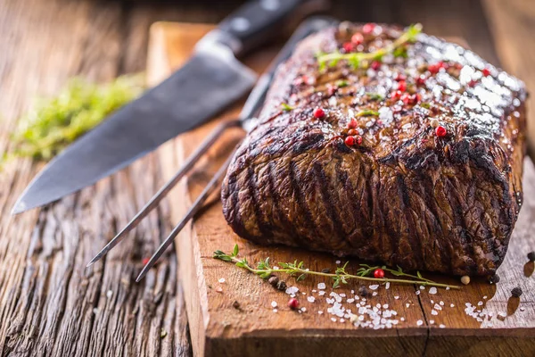 Sığır eti biftek. Ot ve biber ile ahşap tahta üzerinde tavada sulu kaburga eti
