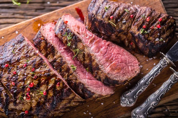 Sığır eti biftek. Sulu orta kaburga biftek dilimleri ahşap tahta çatal ve bıçak otlar baharatlar ve tuz ile