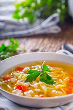 Tavuk suyu. Kemik suyu erişte havuç ve beyaz kase maydanoz ile