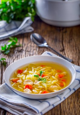 Tavuk suyu. Kemik suyu erişte havuç ve beyaz kase maydanoz ile