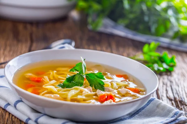 Tavuk suyu. Kemik suyu erişte havuç ve beyaz kase maydanoz ile