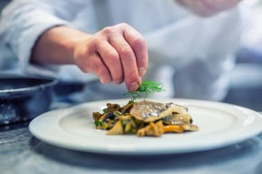 Şef otel ya da Restoran mutfak yemek, sadece eller. Dereotu dekorasyonu ile hazırlanmış balık biftek