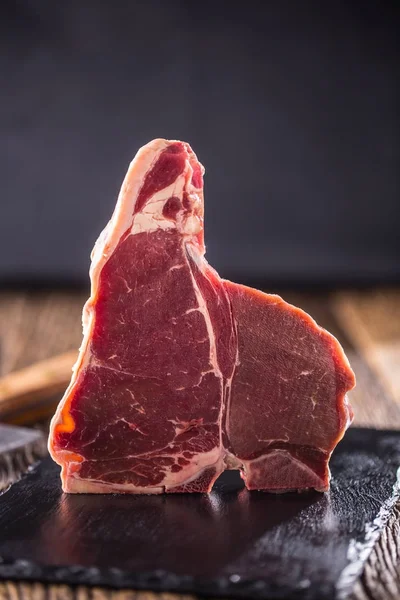 Biefstuk T-bone. Rauwe biefstuk T-bone op leisteen bord met zout peper kruiden slager en vork — Stockfoto