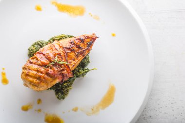 Tavuk ızgara göğsü. Pastırma ve ıspanak üzerinde beyaz plaka ile kavrulmuş tavuk göğsü