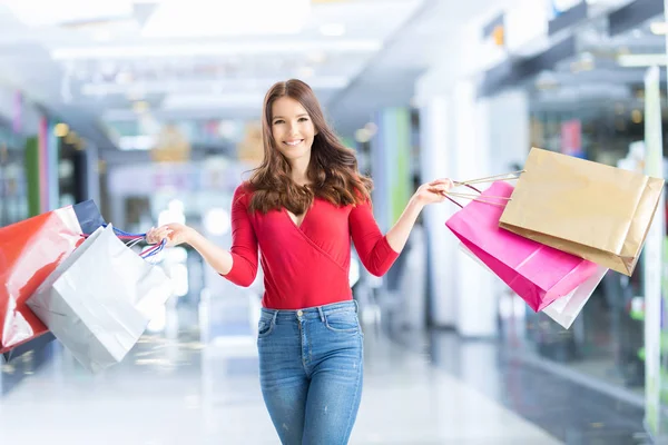 Menina feliz bonita com cartão de crédito e sacos de compras no shopping center. Shopping Center em segundo plano — Fotografia de Stock