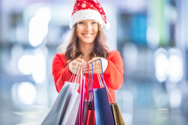 Les courses de Noël. Jolie fille heureuse avec carte de crédit et sacs à provisions en chapeau de Père Noël — Photo