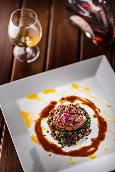 Bife de vaca. Bife de carne grelhada lentilhas pretas misturadas com vegetais. Conhaque ou conhaque como bebida. Comida culinária em hotel pub ou restaurante — Fotografia de Stock