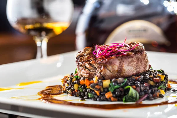 Bife de vaca. Bife de carne grelhada lentilhas pretas misturadas com vegetais. Conhaque ou conhaque como bebida. Comida culinária em hotel pub ou restaurante — Fotografia de Stock