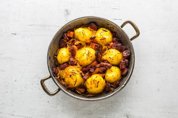 Potatoes. Roasted potatoes with bacon onion and sausages on whit concrete table