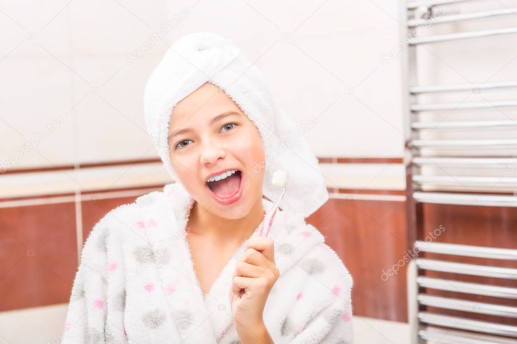 Teenage girl in bathroom with toothbrush. Morning and evening dental hygiene