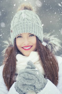 Sıcak giysiler içinde güzel gülümseyen genç kadın. Portre kış karlı havalarda kavramı