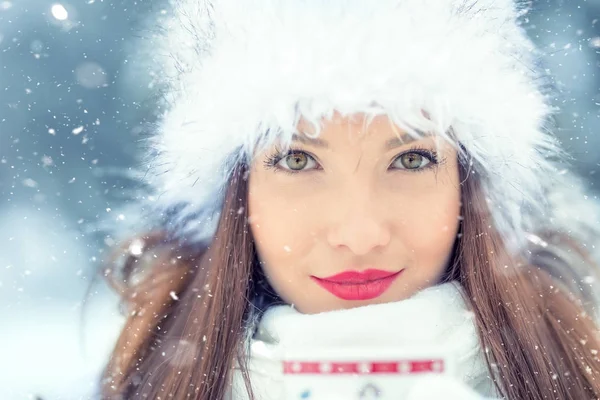 Beautiful smiling young woman in warm clothing with cup of  hot tea coffee or punch. The concept of portrait in winter snowy weather