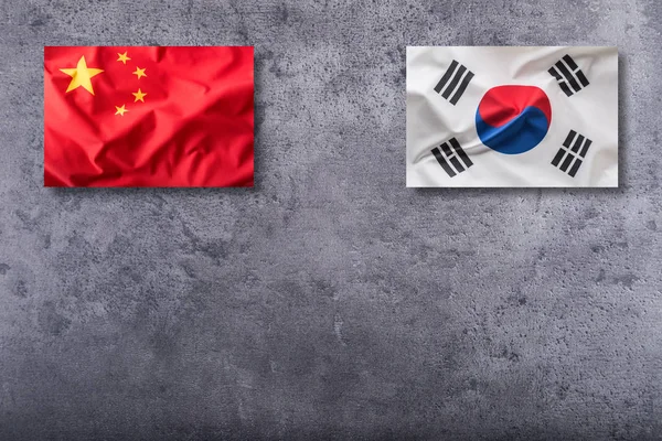 Čína a Jižní korea vlajka na konkrétní pozadí — Stock fotografie