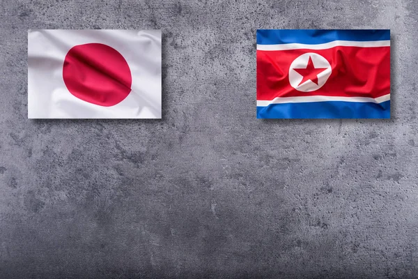 Bandiere Corea del Nord e Giappone. Corea del Nord e Giappone bandiera su concr — Foto Stock