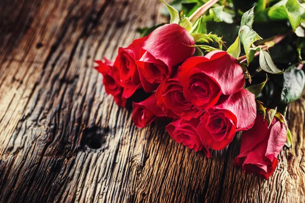 Rosas rojas. Ramo de rosas rojas gratis tumbado en la mesa de roble rústico — Foto de Stock