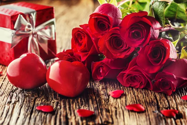 Concepto de boda San Valentín. Ramo de rosas y regalo envuelto con corazones rojos en mesa de madera — Foto de Stock