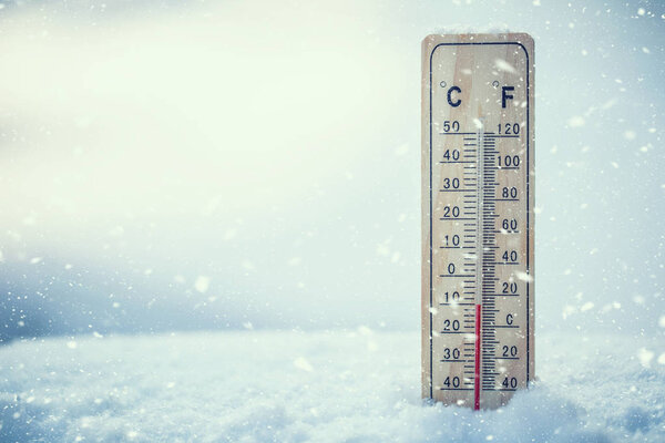 Thermometer on snow shows low temperatures under zero.