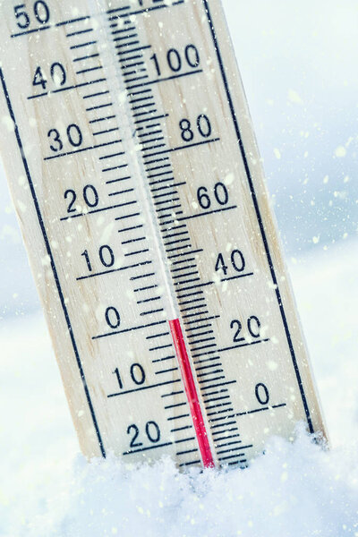 Thermometer on snow shows low temperatures zero.