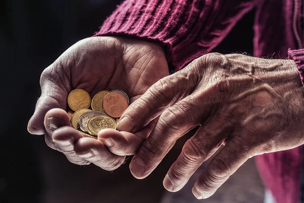 Pensioner man holding in hands euro coins. Theme of low pensions
