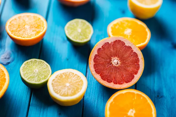 Naranjas limet limón y pomelo sobre mesa azul . — Foto de Stock