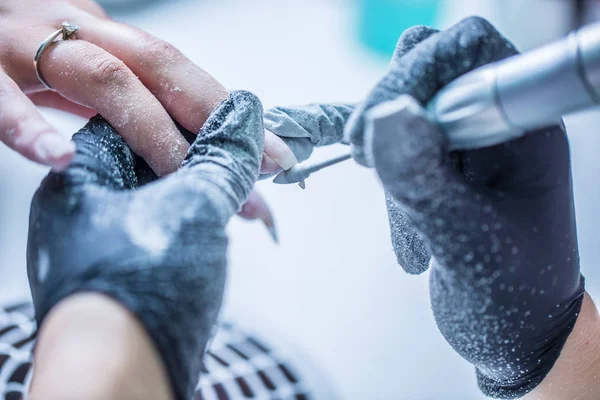 La reparación de las uñas viejas de gel con un molinillo de uñas en el estudio de uñas - salón. el proceso de sustitución de las uñas de gel viejas por otras nuevas. Manicura de uñas — Foto de Stock