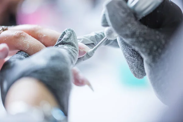 La reparación de las uñas viejas de gel con un molinillo de uñas en el estudio de uñas - salón. el proceso de sustitución de las uñas de gel viejas por otras nuevas. Manicura de uñas — Foto de Stock