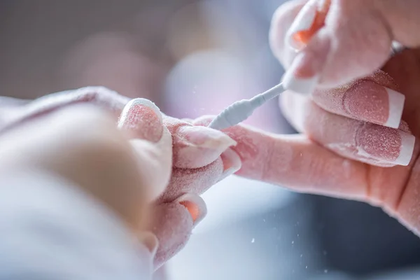 La reparación de las uñas viejas de gel con un molinillo de uñas en el estudio de uñas - salón. el proceso de sustitución de las uñas de gel viejas por otras nuevas. Manicura de uñas — Foto de Stock