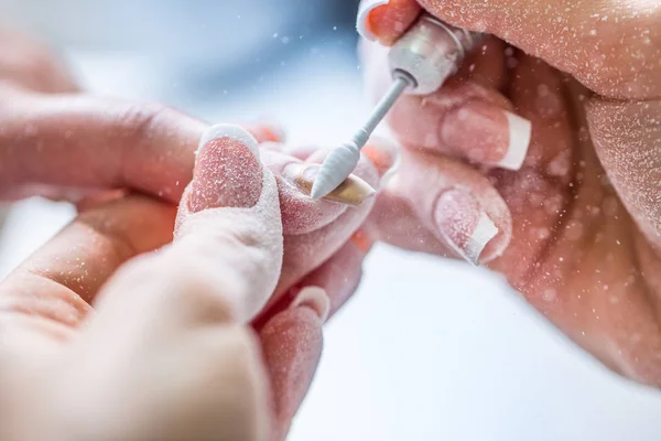 La reparación de las uñas viejas de gel con un molinillo de uñas en el estudio de uñas - salón. el proceso de sustitución de las uñas de gel viejas por otras nuevas. Manicura de uñas — Foto de Stock