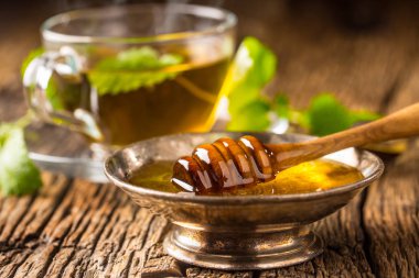 Tatlım. Bal ve bal ayı rustik meşe masada. Arka planda sıcak bitki çayı