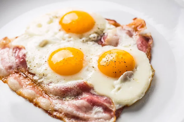 Ham and Eggs. Bacon and Eggs. Salted egg with pepper on white plate. English breakfast — Stock Photo, Image