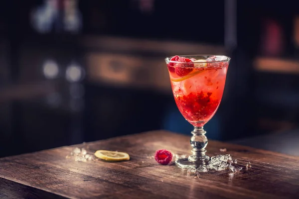 Алкогольный напиток с малиной и лимоном на барной стойке — стоковое фото