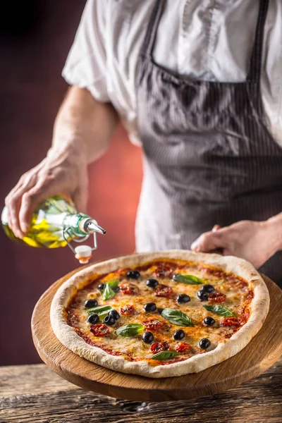 Chef and pizza. Chef pouring olive oil on  pizza in hotel or res