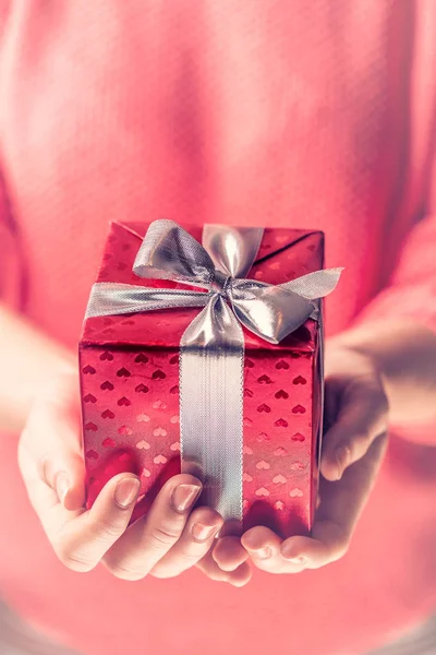 シルバー リボンで包まれた赤い贈り物を保持している女性の手. — ストック写真