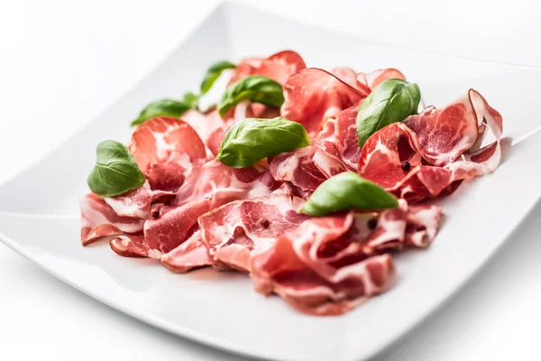 Prosciutto. Gekrulde segmenten van heerlijke Italiaanse Prosciutto met basilicum — Stockfoto