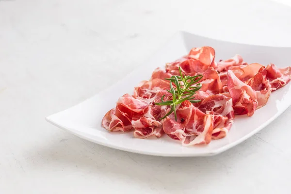 Prosciutto. Gekrulde segmenten van heerlijke Italiaanse ham met rozemarijn — Stockfoto