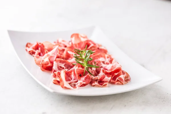 Prosciutto. Gekrulde segmenten van heerlijke Italiaanse ham met rozemarijn — Stockfoto