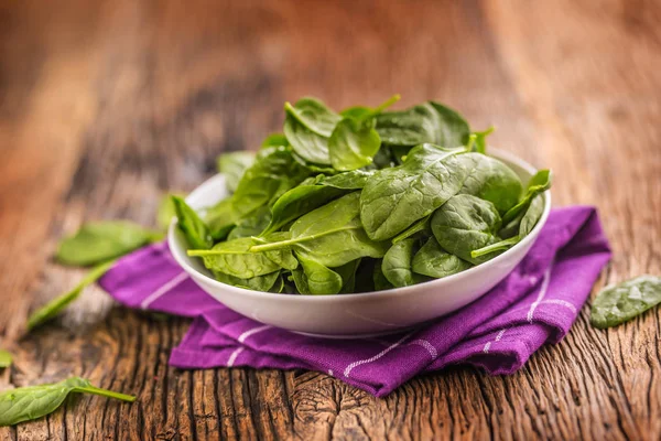 Spinach. Fresh baby spinach leaves in plate on woden table — Stock Photo, Image