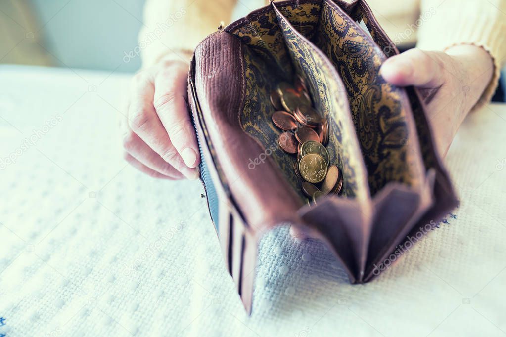 Pensioner woman holding in hands wallet with euro coins