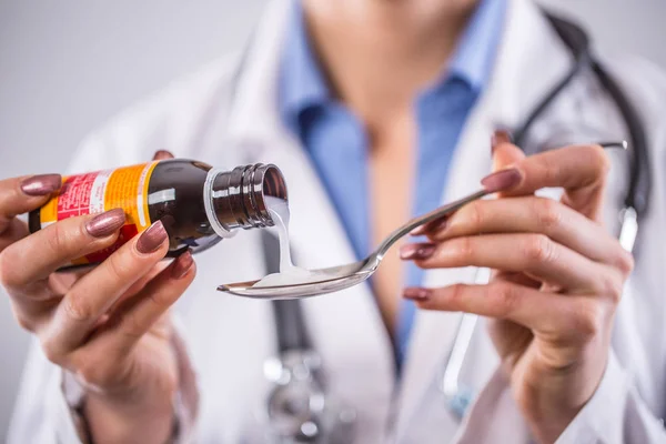 Mãos de jovem médico derramando xarope medicinal na colher — Fotografia de Stock