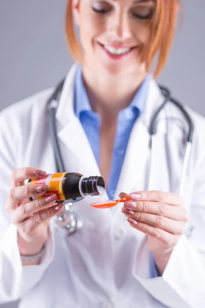 Manos de la joven doctora vertiendo jarabe medicinal sobre cuchara — Foto de Stock