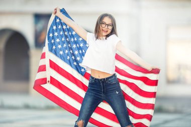 Holding ve şehrin ABD bayrağı sallayarak mutlu genç Amerikan liseli kız