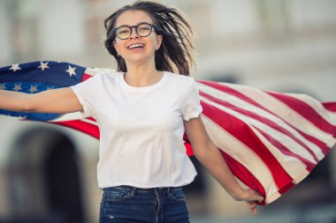 Holding ve şehrin ABD bayrağı sallayarak mutlu genç Amerikan liseli kız