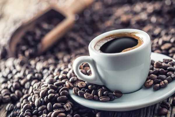 Kubek czarnej kawy z fasolą na drewnianym stole — Zdjęcie stockowe