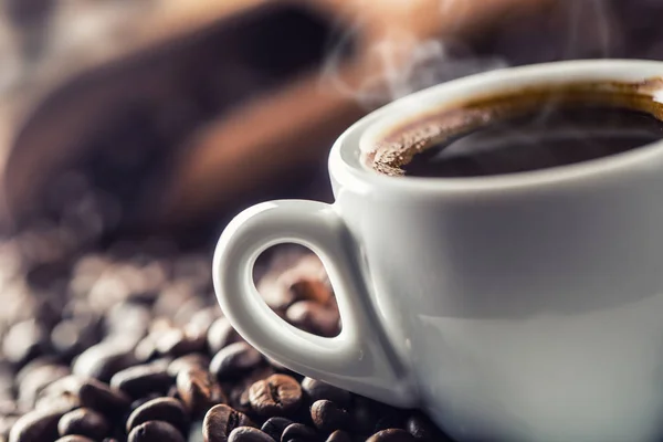 Xícara de café preto com feijão na mesa de madeira — Fotografia de Stock