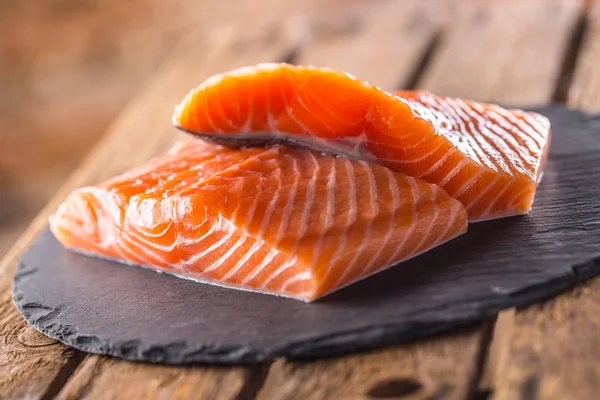 Filetes de salmón crudo en pizarra y tablero de madera — Foto de Stock