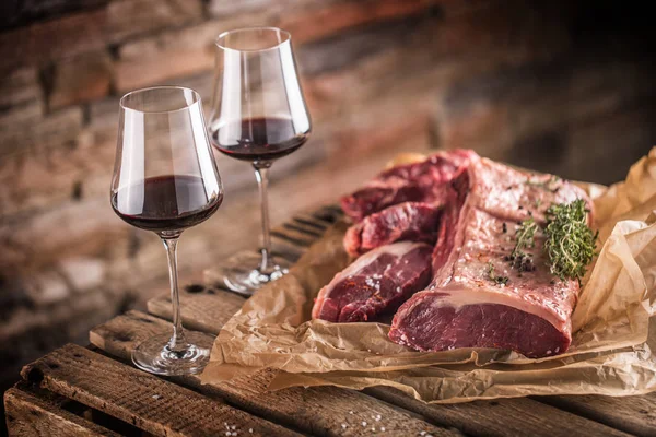 Dos tazas con vino tinto y filete de carne cruda sobre mesa de madera —  Fotos de Stock