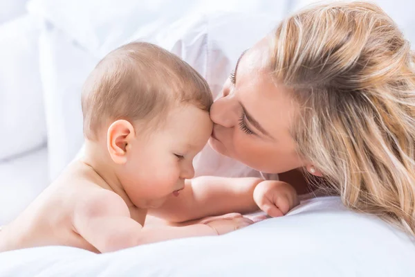 Mãe e bebê menino filho brincando em uma cama branca. Tendência das mães — Fotografia de Stock